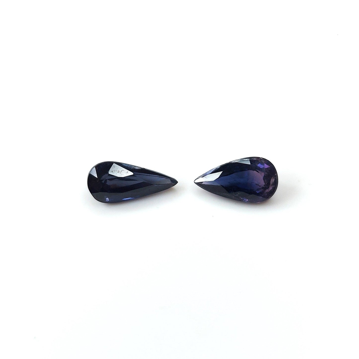 Two pear-shaped blood blue sapphires placed side by side on a white background.