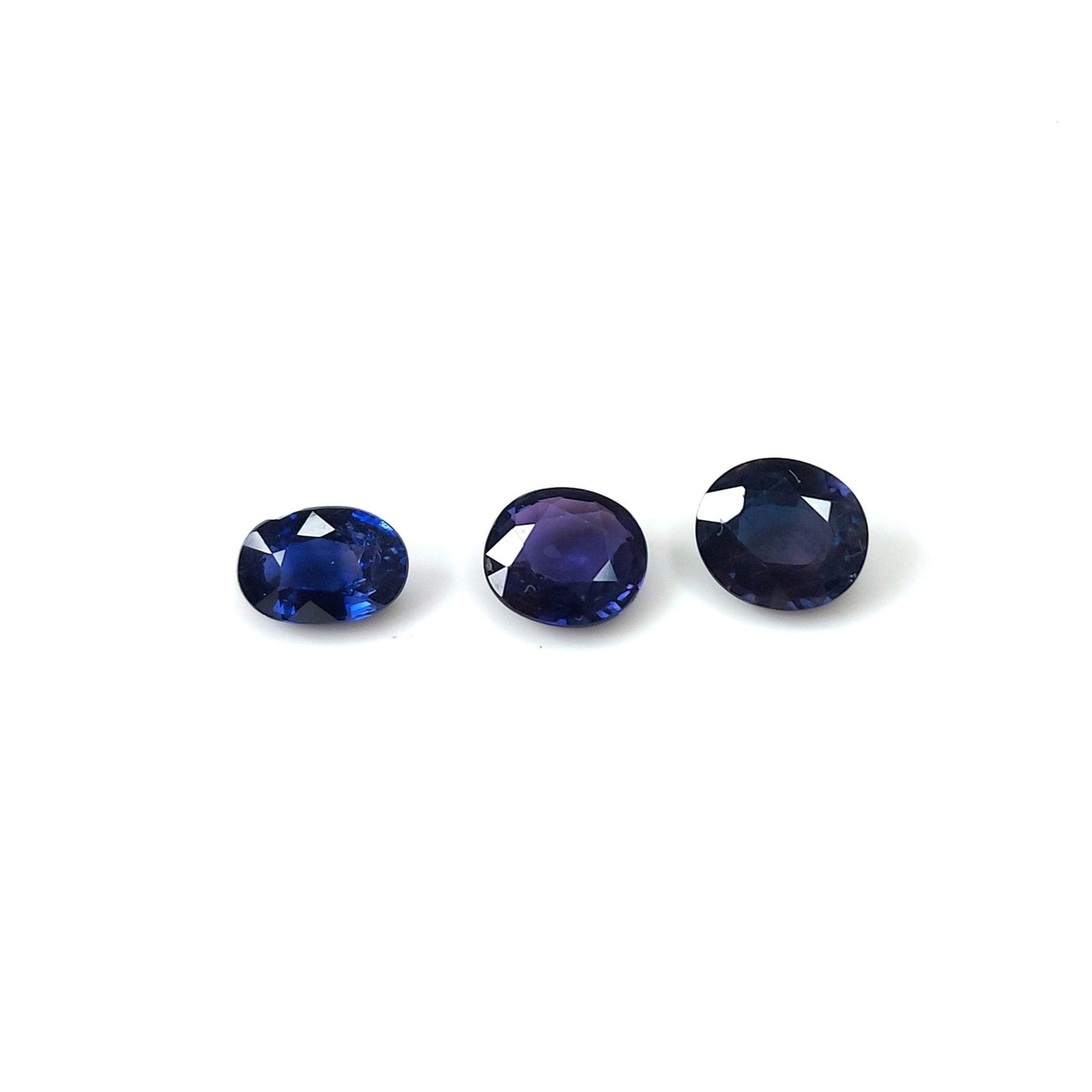 Three oval-shaped blood blue sapphires arranged in a line on a white background.